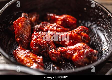 Ailes de poulet marinées épicées dans une casserole sombre. Banque D'Images