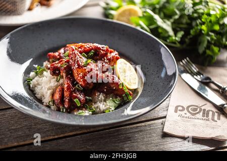 Poulet glacé au miel de style asiatique, feuilles de coriandre, riz et citron. Banque D'Images