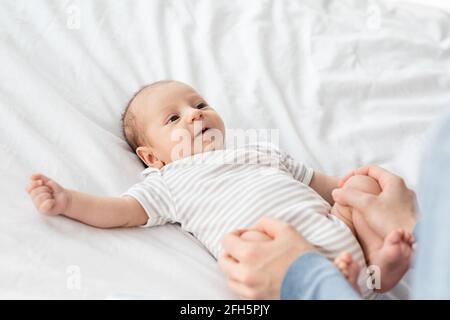 Gymnastique de bébé. Mère méconnaissable faisant des exercices de stronage pour enfant nouveau-né à la maison Banque D'Images