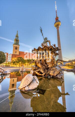 La fontaine Neptune à Alexanderplatz à Berlin au lever du soleil avec Le célèbre Fernsehturm et le Marienkirche Banque D'Images