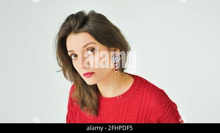 Studio portrait de la jeune femme en chandail tricoté rouge et contour d'oreille sur fond blanc Banque D'Images