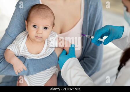 Vaccination. Médecin pédiatre méconnaissable donnant un vaccin contre le petit bébé en clinique Banque D'Images
