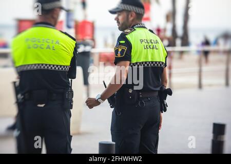 Formation de l'équipe de police espagnole vue arrière avec logo "police locale" emblème sur uniforme maintenir l'ordre public dans les rues d'Alicante, Espagne Banque D'Images