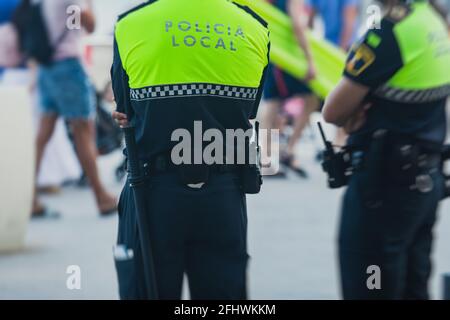 Formation de l'équipe de police espagnole vue arrière avec logo "police locale" emblème sur uniforme maintenir l'ordre public dans les rues d'Alicante, Espagne Banque D'Images