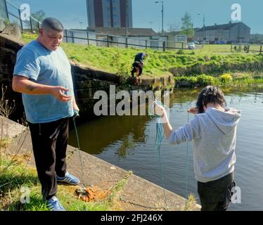 Glasgow, Écosse, Royaume-Uni. 25 avril 2021. Météo britannique : ensoleillé avec la fin du confinement en vue a amené les gens sur le canal Forth et clyde il est maintenant autorisé à attirer la pêche après que le conseil a décidé hier de l'autoriser et les habitants à l'entrée de la chapelle de tambour ont découvert qu'il était plein de trésors douteux . Crédit : Gerard Ferry/Alamy Live News Banque D'Images