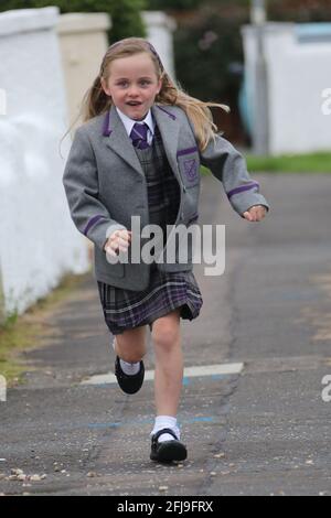 Ayrshire, Écosse, 20 août 2018. Premier jour de l'école primaire. Petite fille qui court sur le trottoir dans l'uniforme de la nouvelle école Banque D'Images