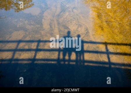 Ombres de deux figures sur un pont en rivière avec des reflets d'arbres - Écosse, Royaume-Uni Banque D'Images