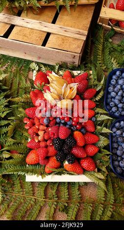 Gros plan d'un mélange de baies comprenant des mûres, des fraises, des bleuets, des framboises et des feuilles fraîches Banque D'Images