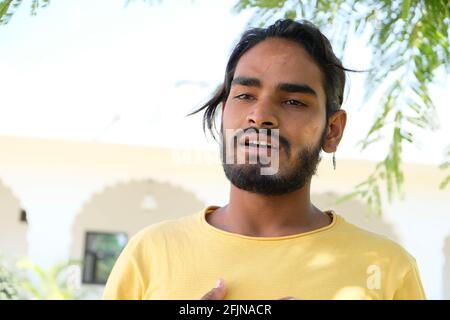 Un jeune homme indien barbu portant un t-shirt jaune pour éternuer dans un parc Banque D'Images