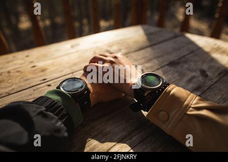 La main d'une femme dans les montres intelligentes tient la main d'un homme dans les montres intelligentes sur les vacances dans la nature. Banque D'Images