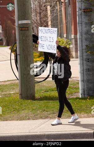 Vaughan, Canada - le 25 avril 2021 : une femme qui détient des médias traditionnels est le signe du virus en signe de protestation contre les mesures de fermeture de la COVID-19 en Ontario Banque D'Images