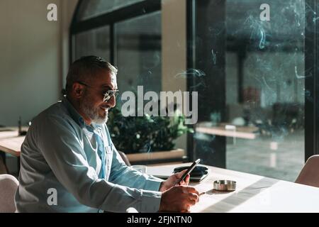 Homme barbu d'âge moyen regardant son téléphone. Les gens d'affaires Banque D'Images