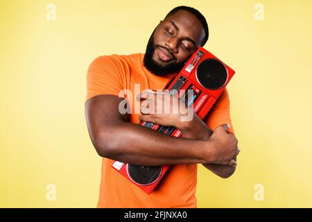 L'homme embrasse une vieille chaîne stéréo. Il aime la musique. Fond jaune Banque D'Images