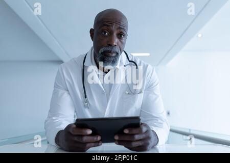Afro-américain médecin tenant un comprimé assis au bureau donnant consultation par appel vidéo Banque D'Images