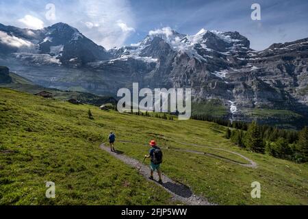 Deux randonneurs sur un sentier de randonnée, en face de la face nord de l'Eiger, derrière les montagnes et les sommets de montagne, la face raide et les montagnes, région de Jungfrau Banque D'Images