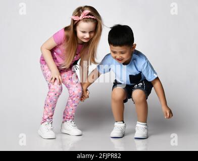 Deux drôle de grenouilles d'enfants amis garçon et fille dans les vêtements d'été se tiennent ensemble regardant vers le bas, a remarqué quelque chose sur le sol Banque D'Images