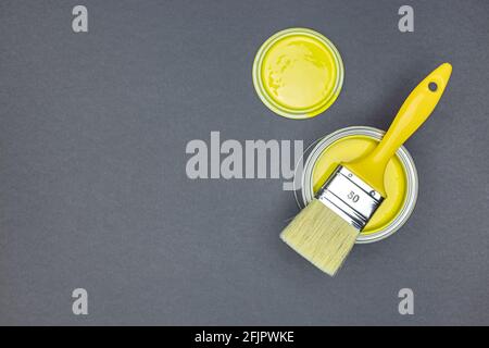 ouvre une couche de peinture jaune avec un pinceau sur fond gris foncé. pose à plat Banque D'Images