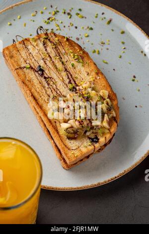 Toast au kiwi, à la banane et au chocolat avec jus d'orange frais. Banque D'Images