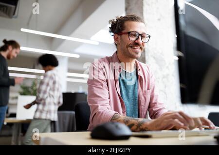 Jeune homme hipster souriant en travaillant sur un bureau d'ordinateur bureau Banque D'Images