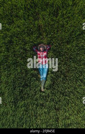 Vue aérienne d'une agricultrice qui se trouve dans un champ de blé vert et qui se repose, haut en bas drone pov de femme agronome dans le wheatgrass Banque D'Images