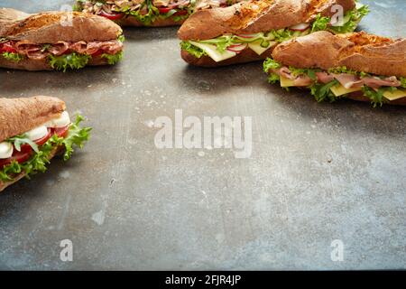 Assortiment de délicieux sandwichs avec légumes et viande placés sur du shabby table grise pendant le déjeuner Banque D'Images