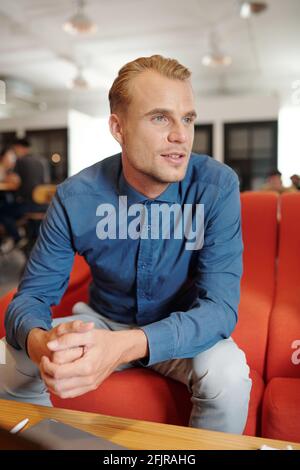 Portrait d'un jeune entrepreneur élégant assis à une table dans un café et en attente d'un partenaire commercial Banque D'Images