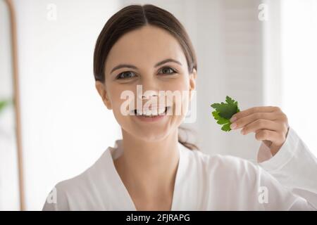 Portrait d'une jeune femme heureuse tenant des feuilles de persil vert frais Banque D'Images