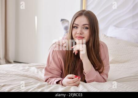 Une jeune femme blanche est au lit sur son ventre, portrait en gros plan. Banque D'Images