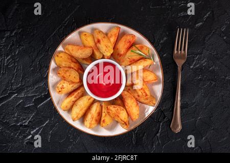 Plat de quartiers de pommes de terre cuits, avec ketchup et romarin Banque D'Images