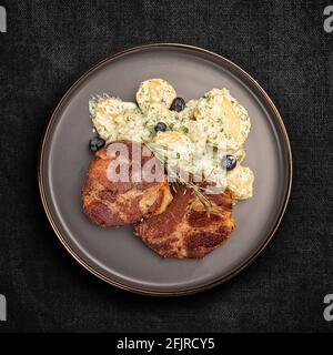 Côtelette de porc juteuse grillée servie avec salade de pommes de terre, vue de dessus, plat Banque D'Images