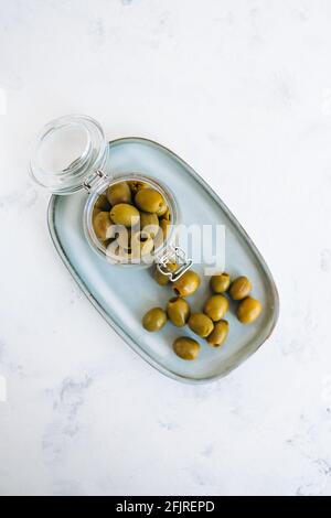 Bol avec olives vertes sur une assiette, vue de dessus. Banque D'Images