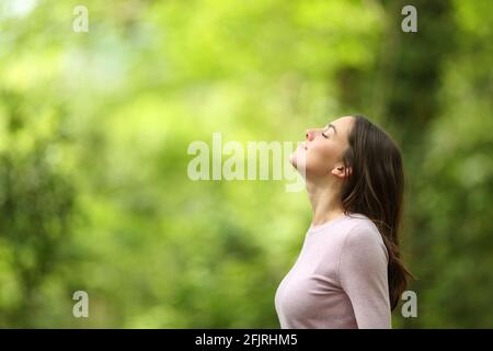 Profil d'une femme détendue respirant de l'air frais dans un forêt verte Banque D'Images