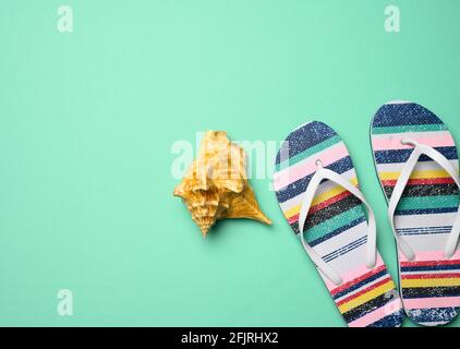 pantoufles multicolores pour femmes et seashell sur fond vert, vue du dessus