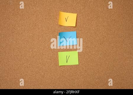 autocollants en papier colorés collés sur un panneau en liège marron, gros plan Banque D'Images