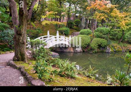 Pont d'arche blanc au-dessus de l'étang au centre de l'ancien jardin Yasuda (Kyu-yasuda Teien), un petit jardin de promenade japonais situé à Ryogoku. Tokyo. Japon Banque D'Images