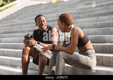 Sportif Black Guy et fille se reposant après l'entraînement sur urbain Étapes Banque D'Images