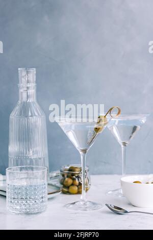 Cocktail de martini dans un verre sur fond bleu avec olives. Banque D'Images