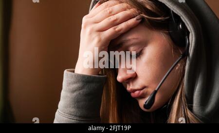 Portrait d'une jeune fille dans un sweat à capuche et avec un casque. Employé de centre d'appels fatigué Banque D'Images