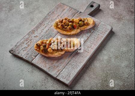 Bruschetta avec caponata sicilien traditionnel maison et pain ciabatta sur planche à découper en bois. Gros plan Banque D'Images