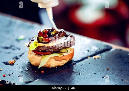 Le chef prépare de la mayonnaise sur un mini-hamburger. Banque D'Images