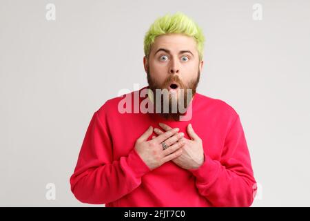 Vue de face de l'homme étonné dans un chandail décontracté debout avec la bouche ouverte dans la surprise, a l'expression choquée, entend des nouvelles incroyables, mains sur la poitrine. Banque D'Images