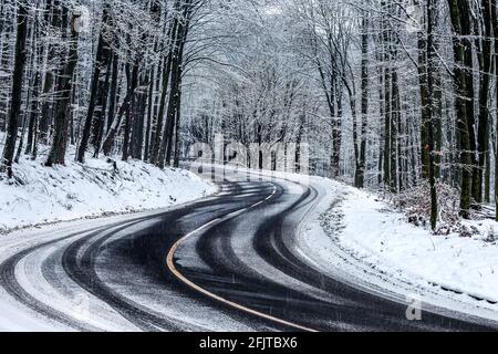 Kekesteto, Hongrie - Winding route d'hiver aux montagnes de Matra près de Kekesteto. Route asphaltée courbée avec des arbres enneigés dans le forset pendant un hiver froid Banque D'Images