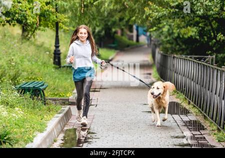 Jeune fille qui court avec un chien après la pluie Banque D'Images