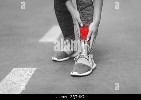 Blessures aux jambes. Femme méconnaissable massant la zone de Shin enflammée avec la zone rouge de la plaie Banque D'Images