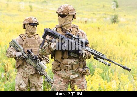 Deux soldats armés et équipés de fusils dans le champ en fleurs, des tireurs d'élite membres de l'équipe de garde-fous Banque D'Images