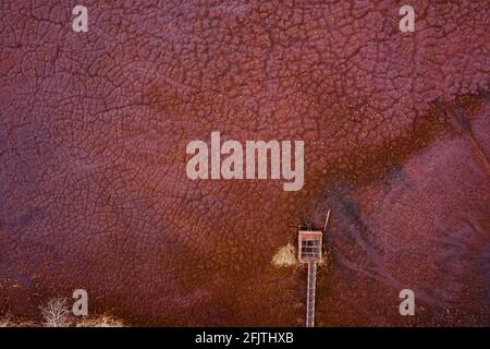 Site de déversement de produits chimiques industriels à partir d'ironlworks, sol rouge sec avec des plantes mortes tuyaux rouillés et empreintes de pattes d'animaux, vue aérienne par drone. Banque D'Images