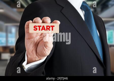 Homme d'affaires montre un bloc de bois avec le mot START. Nouveau début de carrière ou pour commencer un travail ou un projet dans le concept d'affaires. Banque D'Images