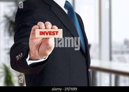 Homme d'affaires montre un bloc de bois avec le mot investir. Concept de décision d'investissement financier. Banque D'Images