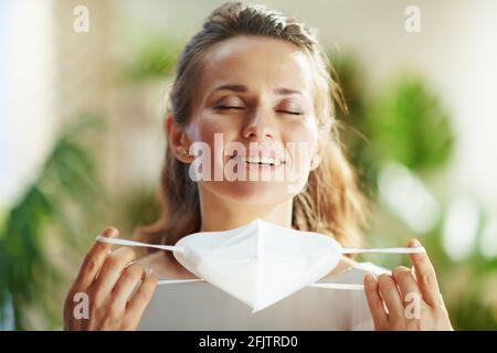 pandémie covid-19. Portrait d'une femme moderne et décontractée de 40 ans en blouse grise qui prend le masque ffp2. Banque D'Images