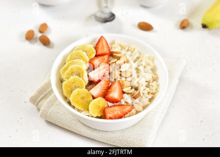 Porridge à flocons d'avoine maison avec fraise, banane et noix dans un bol Banque D'Images